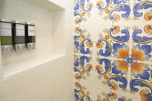 A bathroom with a tiled wall featuring a floral pattern and three dispensers labeled 'shampoo,' 'shampoo,' and 'body wash.' - Ricomincio da Tre (Sorrento)
