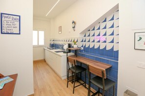 Eine moderne Küche mit Barbereich, einem Schild mit Hausordnung und einer blauen und weißen Fliesenwand.