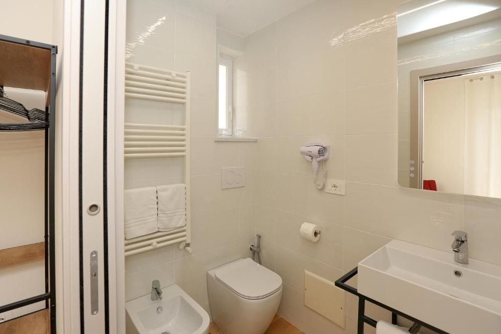 Un baño con inodoro, bidé, lavabo, toallero y secador de pelo.