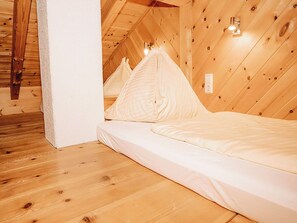 Ein Schlafzimmer mit Holzboden und -wänden, einem Bett mit weißer Bettwäsche und einer Wandleuchte.