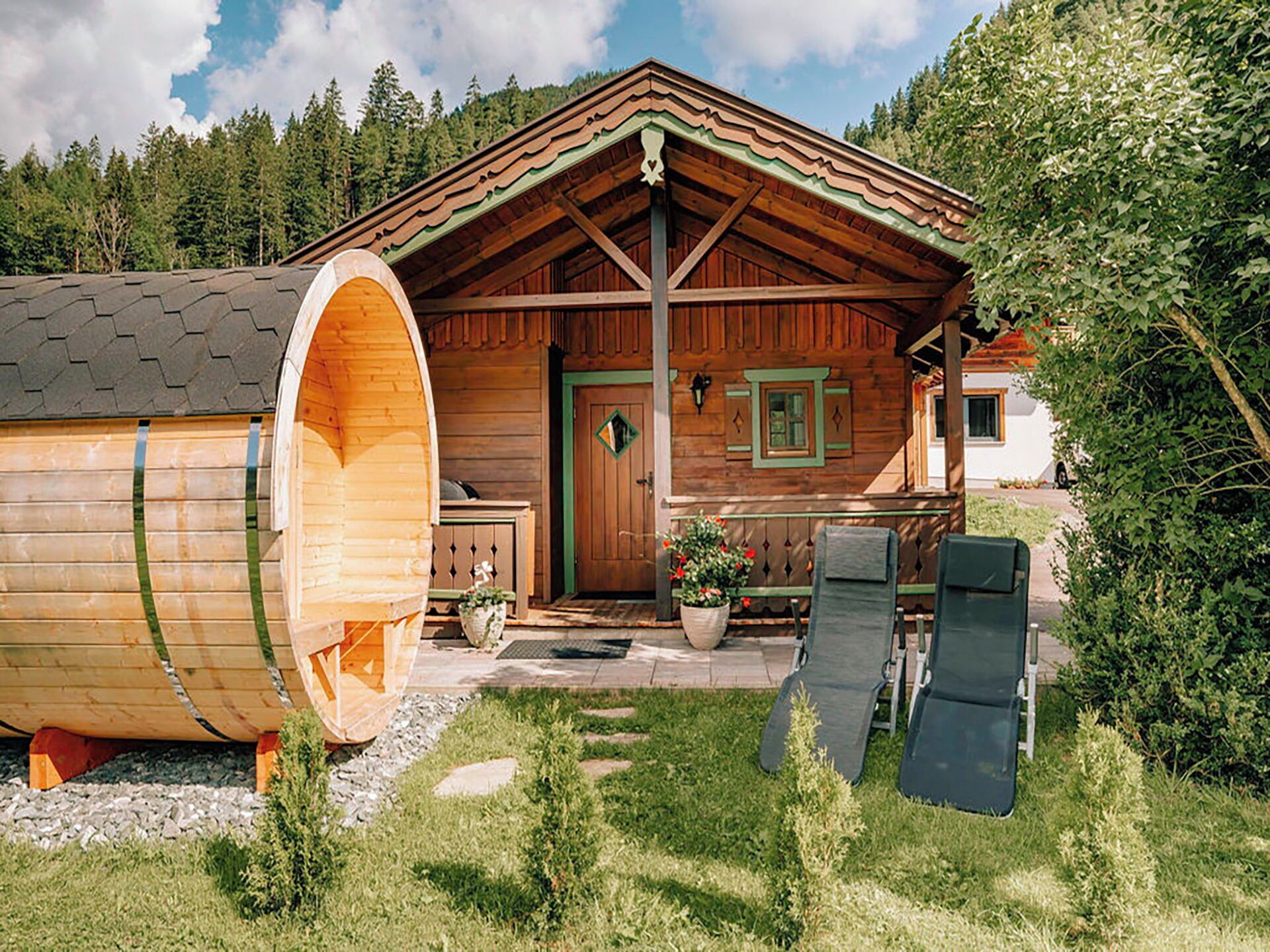 A wooden cabin with a large barrel-shaped structure attached to the front, a wooden porch, and a door with a green frame.