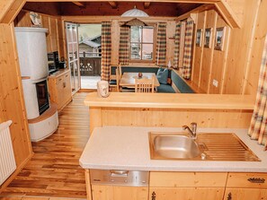 Ein gemütliches Blockhaus-Interieur mit Küchenzeile, Essbereich und Blick ins Freie.