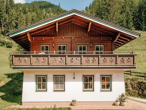 Eine Chalet mit Balkon, Holzfassade und vielen Fenstern.
