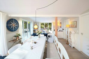 Uma sala de jantar com uma mesa grande, cadeiras, um lustre e uma bússola fixada na parede.