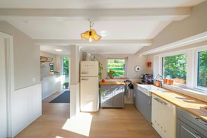 Cozinha moderna com geladeira, pia e bancada de madeira.
