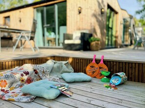 Una terraza de madera con cojines, una manta y una tabla de remo.