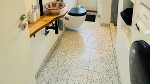 Ein Badezimmer mit rundem Spiegel, Toilette, Waschbecken und Regalen.
