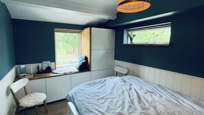 Ein Schlafzimmer mit Bett, Stuhl, Schreibtisch und Fenster.