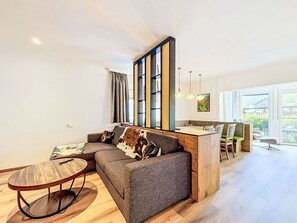 A modern living room with a sofa, a coffee table, and a dining area with chairs. - Stunning private villa for 10 guests with WIFI, TV and terrace (Vergötschen)