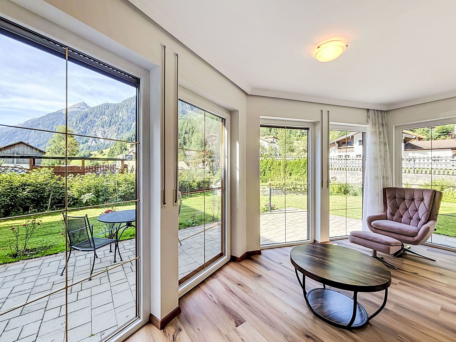 A spacious room with large sliding glass doors leading to a patio, a round table, and a cushioned chair.