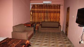 A hotel room with a bed, a sofa, a television, and a curtain.