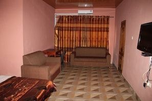 A hotel room with a bed, a sofa, a television, and a curtain. - Sika Towers Hotel limited (Ahenema Kokobin)