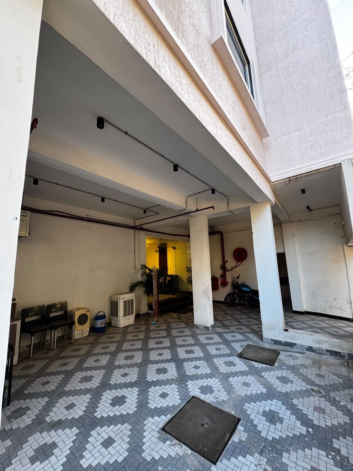Un pasillo descubierto con piso estampado, asientos y una motocicleta.