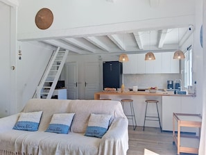 Eine moderne Küche mit weißen Schränken, einem Kühlschrank und einer Holztheke mit Hockern.