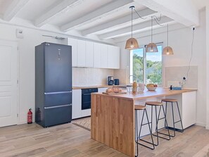 A modern kitchen with a central island, wooden flooring, white cabinetry, and pendant lighting. - Wonderful private villa for 8 guests with private pool, WIFI, A/C, TV and patio (Le Grand-village-plage)