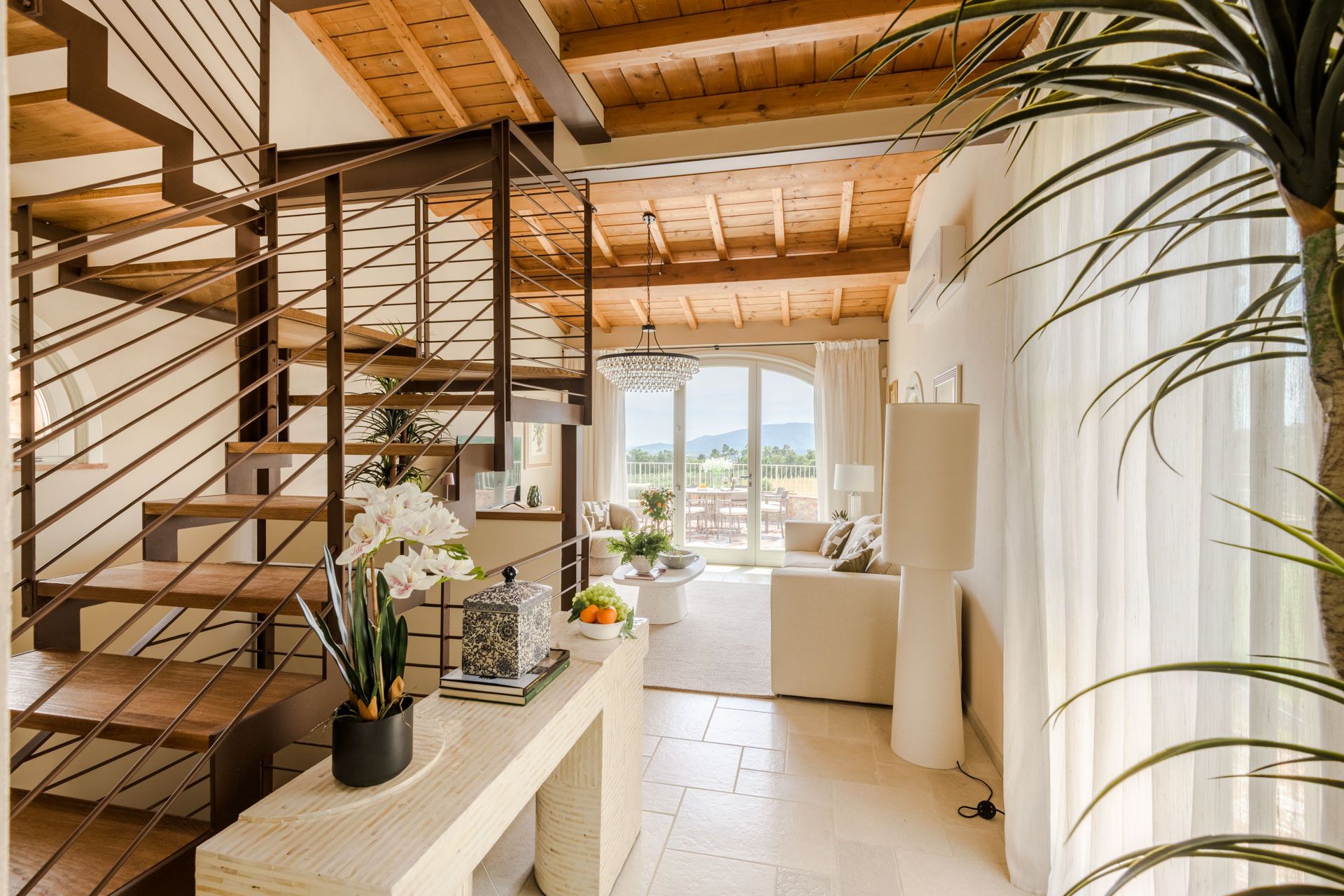 A modern interior with a wooden staircase, a seating area with a view, and a balcony.