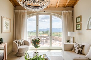 A living room with a large window, a chandelier, and a view of the outdoors. - Villa Altavista in Montecarlo (Montecarlo)