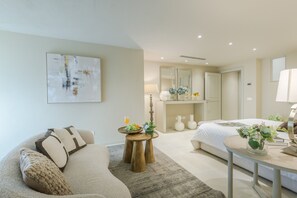 A modern hotel room with a sofa, a bed, a small table with a vase, and a mirror above the bed. - Villa Altavista in Montecarlo (Montecarlo)