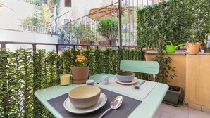 A balcony with a table set for two, a potted plant, and a green watering can. - Urbana Otto - Designer home in the heart of Monti (Roma)