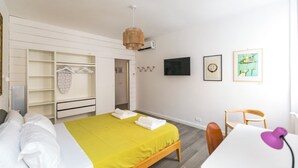 A hotel room with a bed, a desk, a chair, a wardrobe, and a television. - Urbana Otto - Designer home in the heart of Monti (Roma)