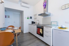Eine moderne Küche mit weißen Schränken, einem eingebauten Ofen, einer Kaffeemaschine und einem kleinen Kühlschrank.
