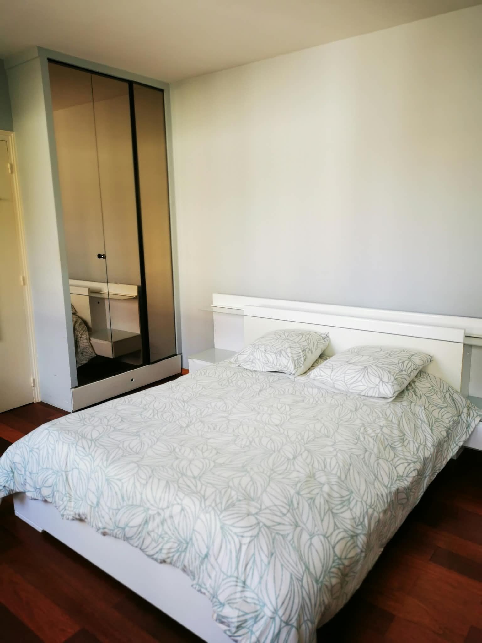 A bedroom with a bed, a wardrobe, and a nightstand.