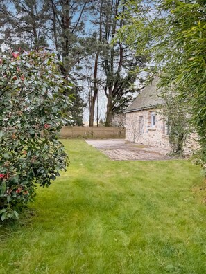 A stone building with a paved area in front, surrounded by trees and a well-maintained lawn. - Cozy house with a large garden (Saint-Avé)