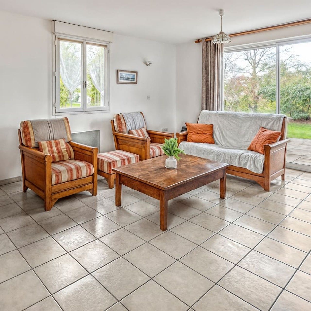 Un salon comprenant un canapé, deux fauteuils, une table basse et une fenêtre avec des rideaux.