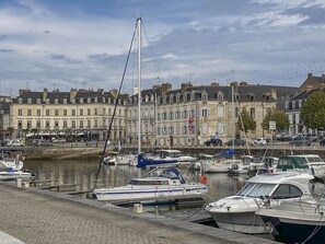 A marina with boats docked, a bridge in the background, and buildings along the waterfront. - Cozy house with a large garden (Saint-Avé)