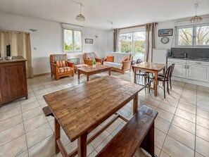 A spacious living area with a wooden dining table, sofas, and a kitchen in the background. - Cozy house with a large garden (Saint-Avé)