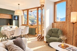 A cozy living area with a sofa, a dining table set for two, and a view of mountains through large windows. - L'Ultime 1800 - Avoriaz - Sleeps 6 - Premium (Morzine)