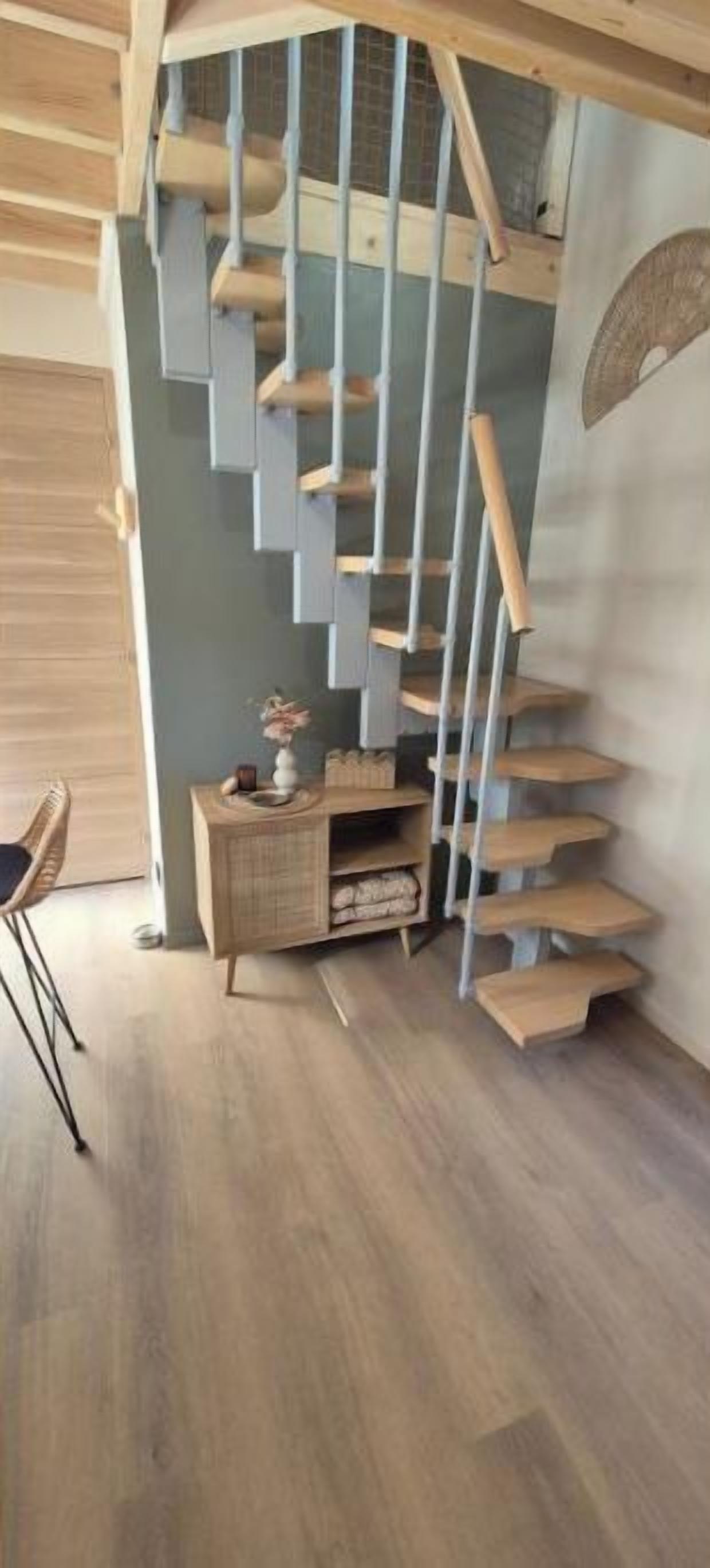 Una escalera de caracol con escalones de madera y barandillas de metal, que conduce a un piso superior.