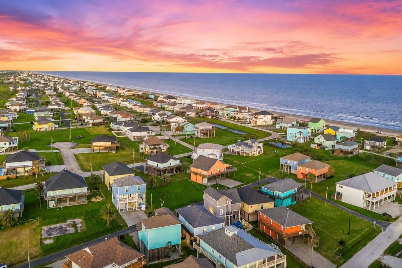 Un quartier résidentiel en bord de mer, avec des maisons, une plage et un coucher de soleil.
