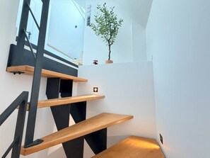 A modern staircase with wooden steps and black railings, leading to a landing with a small potted plant. - Cocon Pierre & Lumière, Cœur de Saint-Patern, Vannes (Vannes)