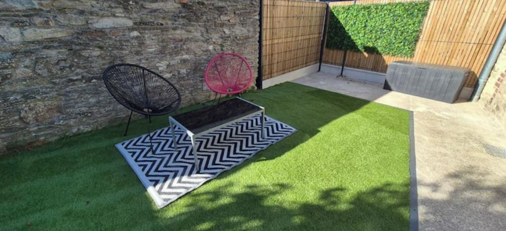 Un espace patio avec un revêtement de sol en gazon synthétique, un tapis à motifs en zigzag, une chaise en métal et une table ronde.