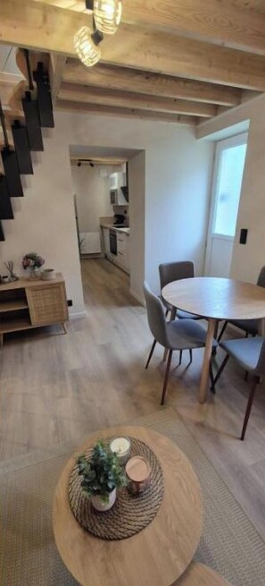 A modern interior with a dining area, a staircase, and a view into a kitchen. - A cozy home, perfect for exploring the Cotentin region (Normandie)