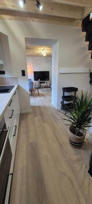A modern kitchen with wooden flooring, a dining area with chairs, and a staircase. - A cozy home, perfect for exploring the Cotentin region (Normandie)