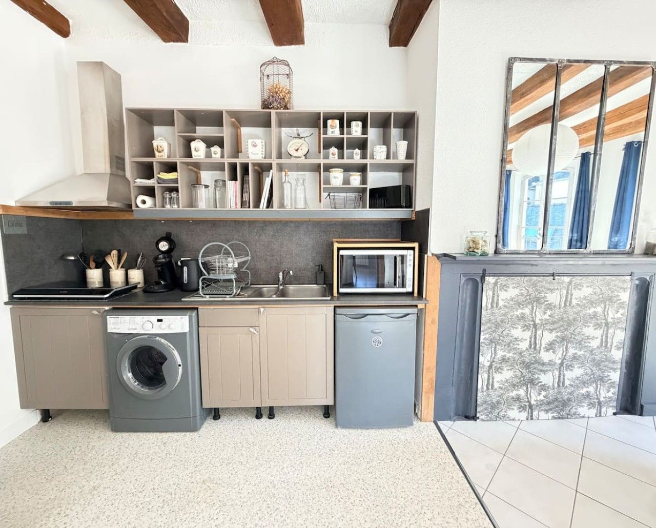 Une cuisine compacte équipée d’un lave-linge, d’un four à micro-ondes et d’un petit réfrigérateur.