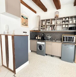 A compact kitchen with a washing machine, a microwave, and a sink. - 2-Bedroom Apartment with Exposed Beams – Historic Center of Vannes (Vannes)