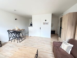 A modern living space with a dining area, a sofa, and a wardrobe. - Modern studio apartment in Vannes, just a stone's throw from the city walls (Vannes)