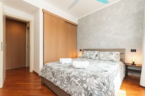 A bedroom with a bed, a nightstand, a wall-mounted lamp, and a door. - New Two-Room Apartment - 100 meters from the Aquarium (Genova)