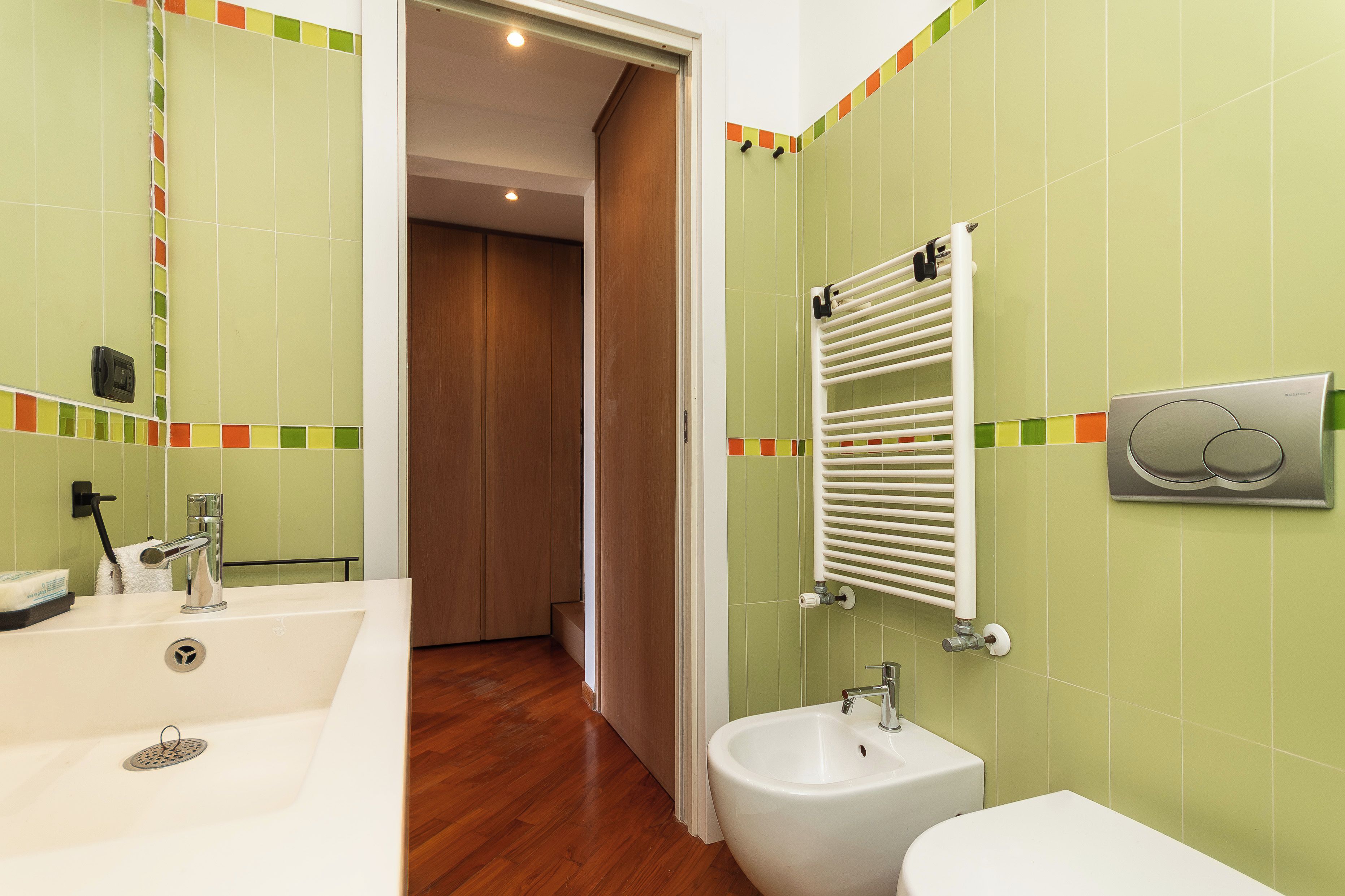 A bathroom with a sink, bidet, and a towel rack.