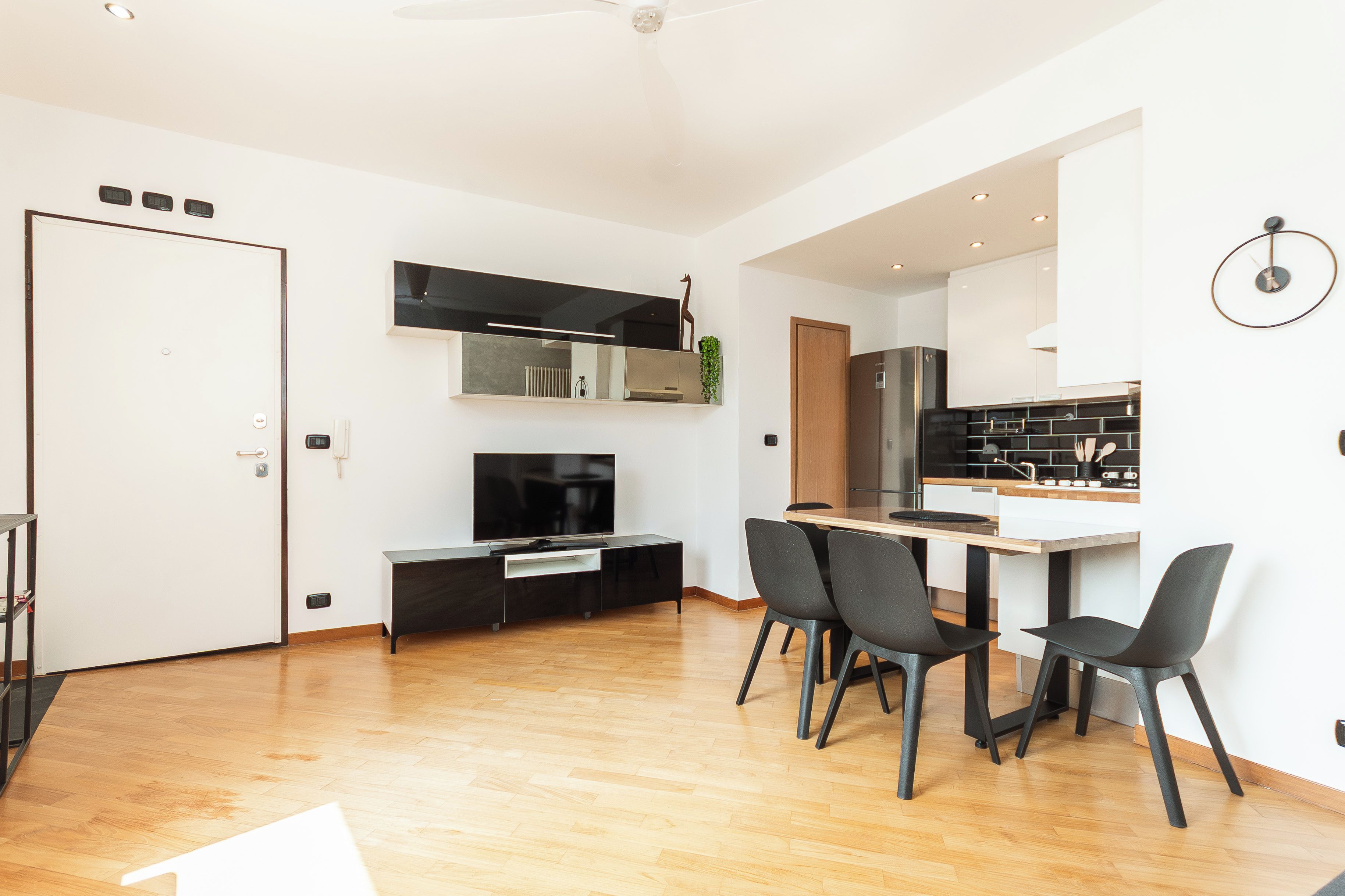 Una cocina moderna con comedor, piso de madera y televisor de pantalla plana.