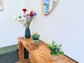 Een houten bankje met een bloemenvaas en een kleine potplant.