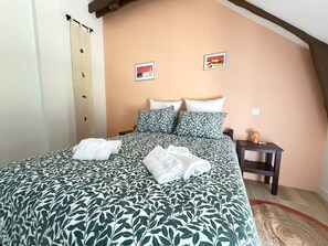 A hotel room with a bed, pillows, a nightstand, and a wall with two pictures. - Charming Vacation Rental - Stone and Wood - Morbihan (Saint-Jean-Brévelay)