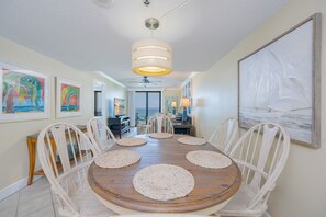 Ein Esszimmer mit einem Holztisch, weißen Stühlen und einem Deckenventilator.