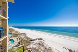 A beachfront hotel with a pool area, a sandy beach, and a clear blue sky. - Phoenix I 1103 2 Bedroom Condo (Orange Beach)