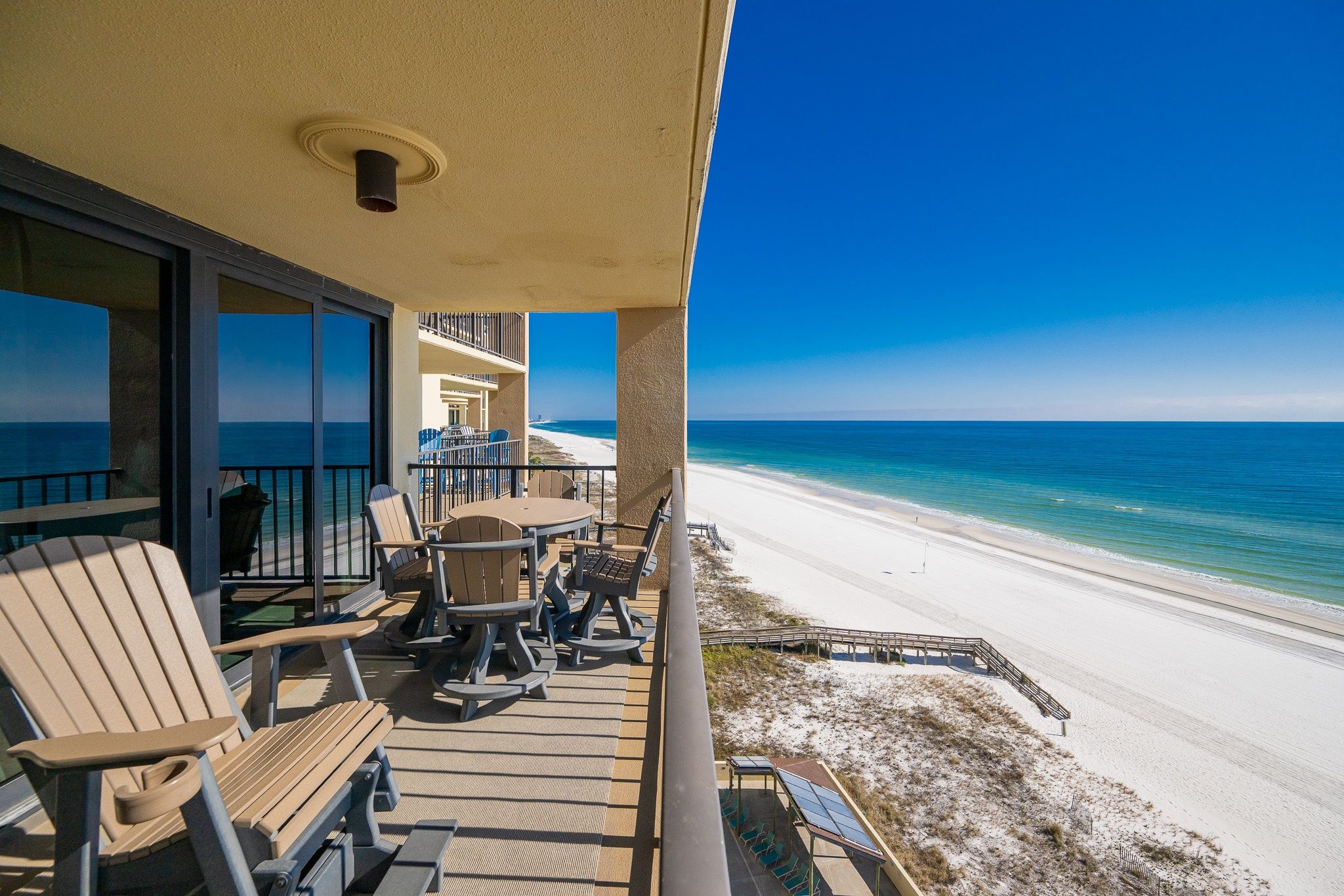 A balcony with outdoor seating overlooking a beach.