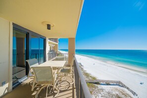 A balcony with a table and chairs overlooking a beach. - Phoenix I 1115 2 Bedroom Condo (Orange Beach)