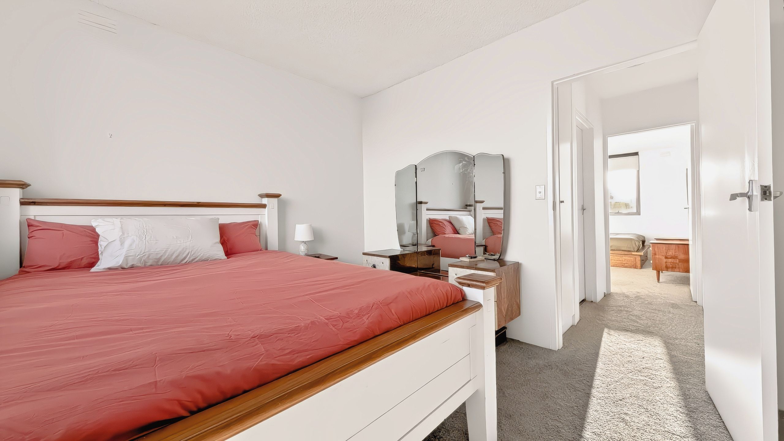 Une chambre à coucher avec un lit, une table de chevet, une lampe et un miroir.
